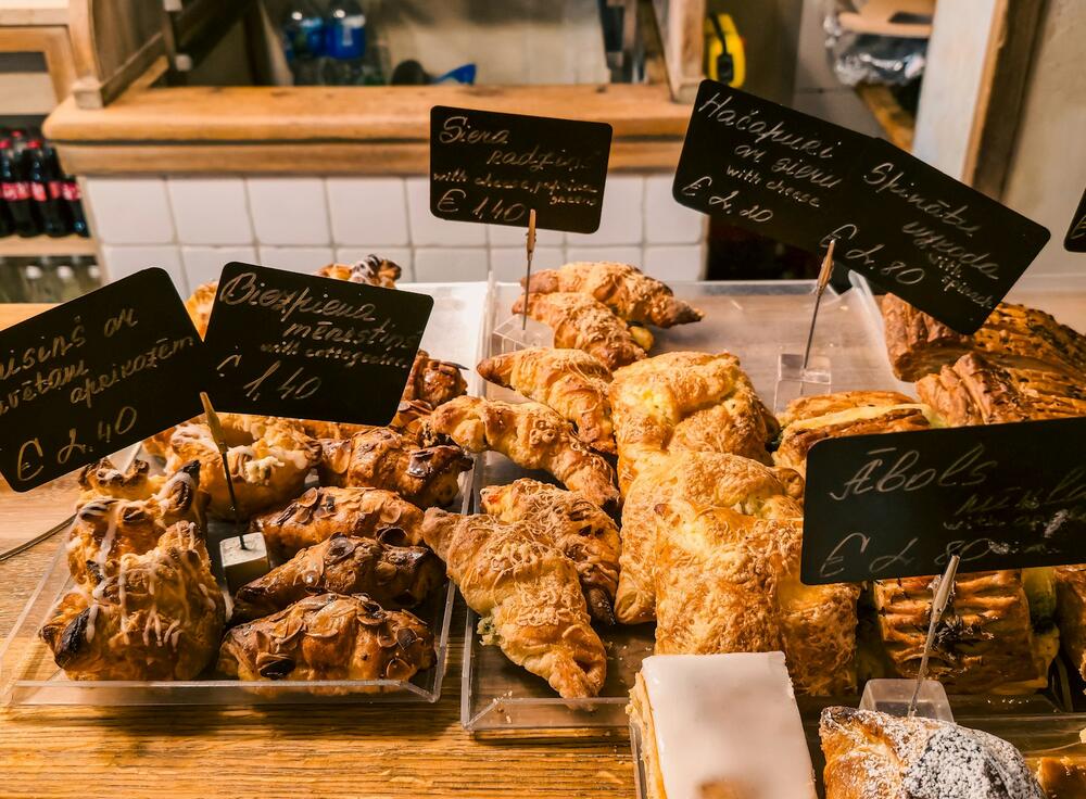 Croissants and buns piled on the counter under chalkboard price signs