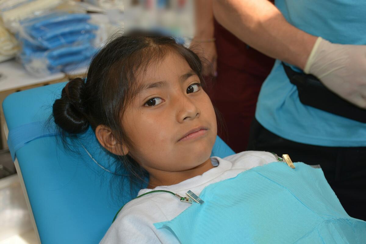 A young girl in a paper bib waiting calmly in the dental chair