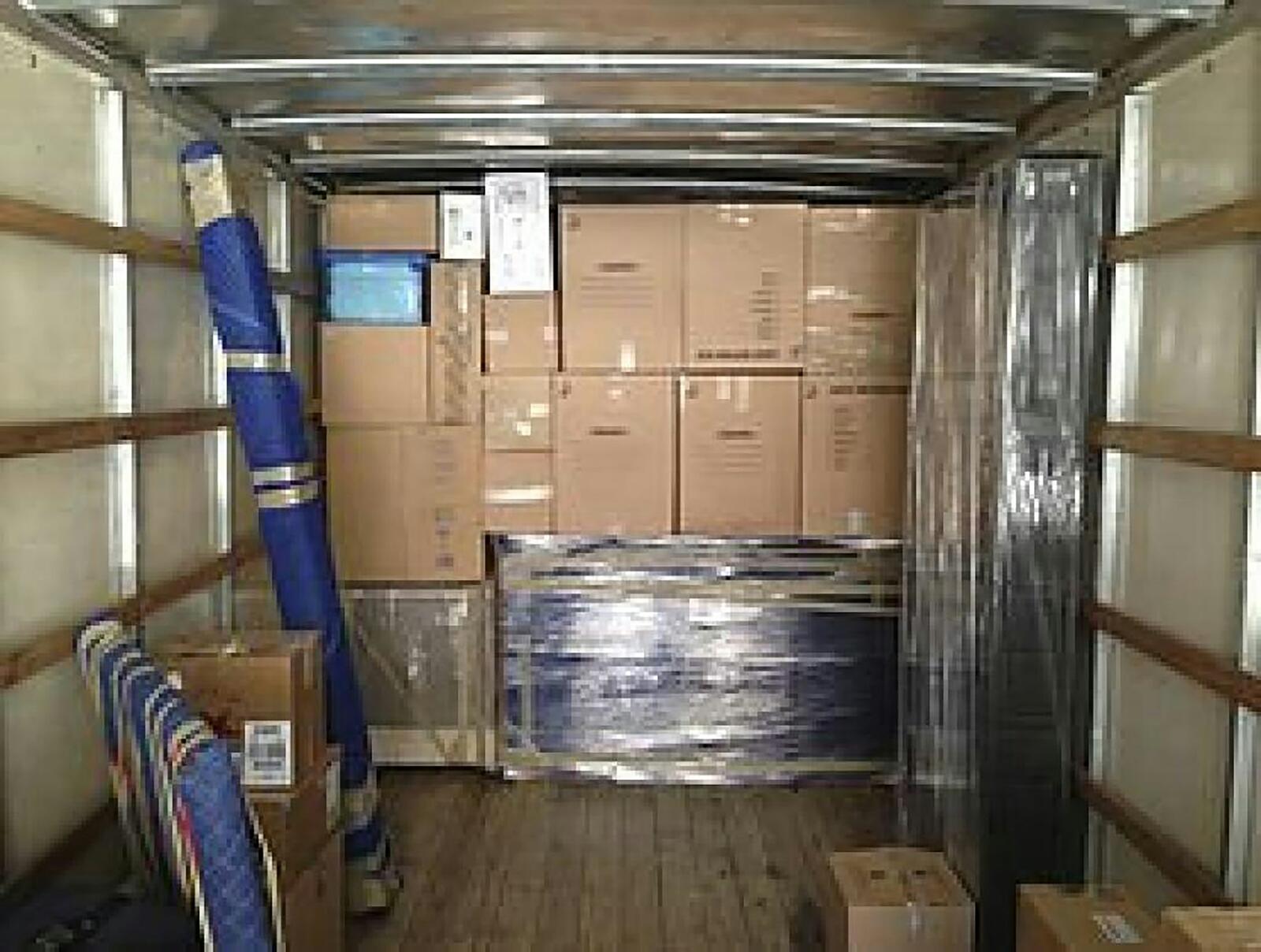The inside of a loaded moving truck: taped boxes, wrapped furniture and padded pieces strapped in