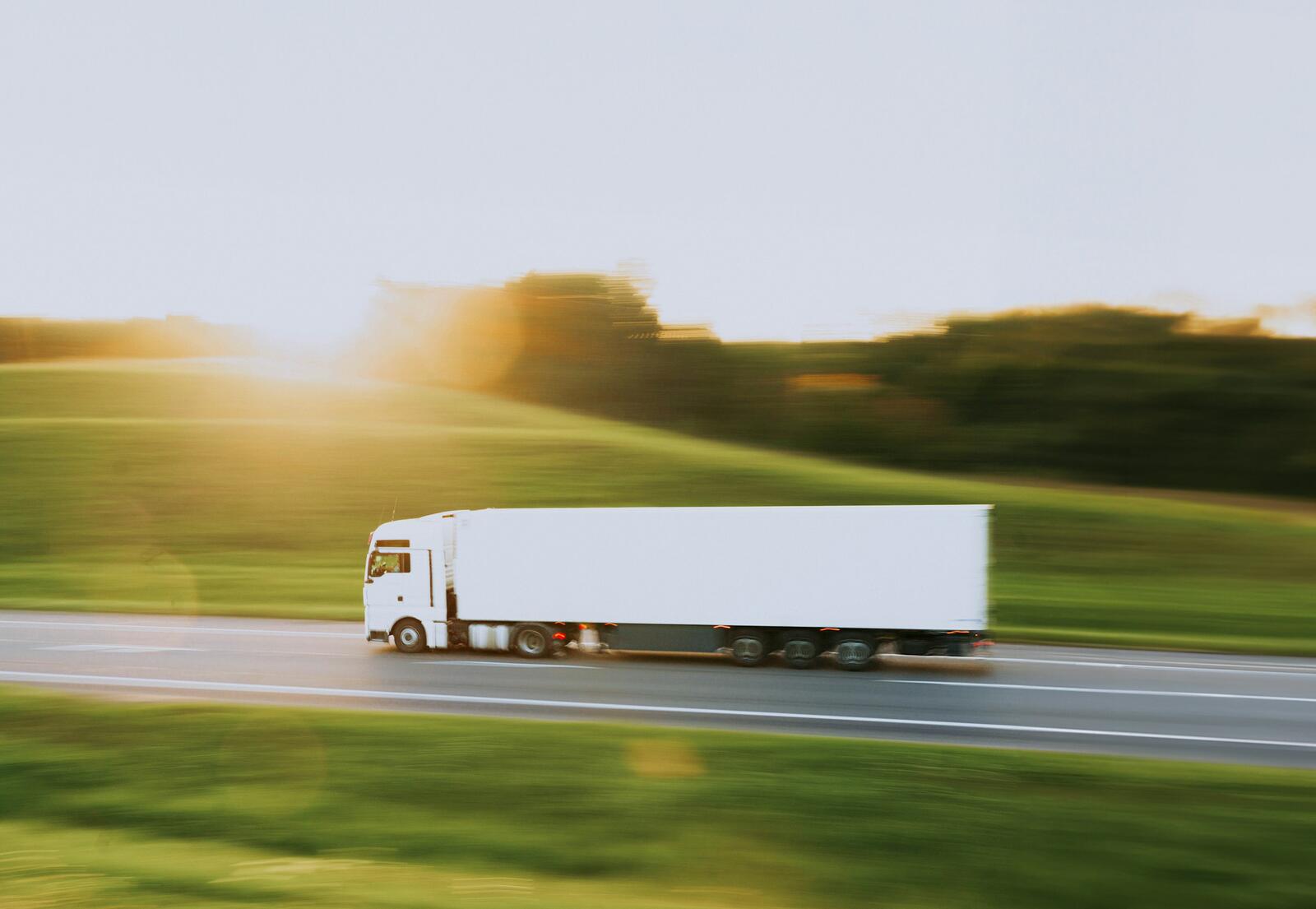 A plain white truck on a rural highway at sunset